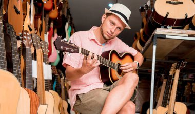 Genç bir müzisyen gitarı gitar dükkanında test ediyor..