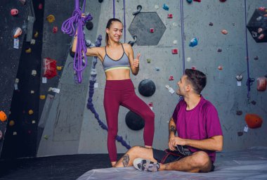 Renkli tutacakları ve ipleri olan yapay bir duvara karşı güçlü bir çift tırmanıcı.