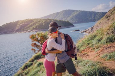 Mutlu genç çift okyanusun yakınındaki dağların zirvesine tırmanıyor..