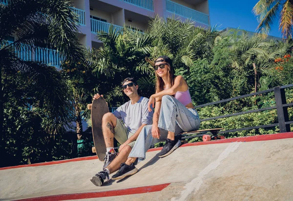 stock image Young happy couple with skateboards enjoy longboarding at the skatepark.