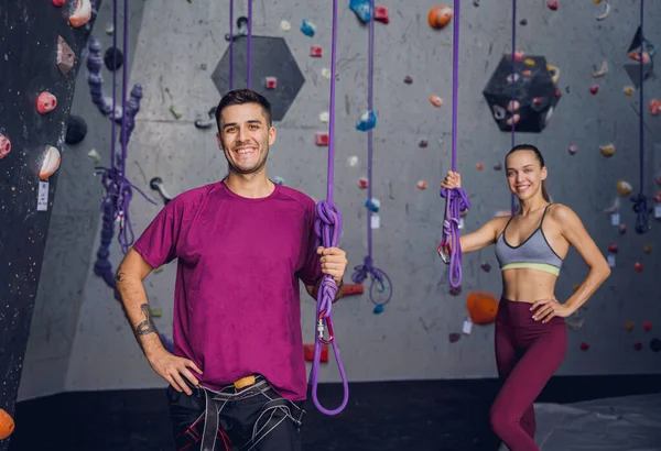 カラフルなグリップとロープを持つ人工的な壁に対する強力なカップルの登山者 — ストック写真