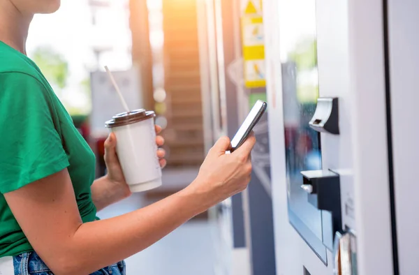 非接触支払い方法を使用して自動販売機でコーヒーを支払う若い女性 — ストック写真