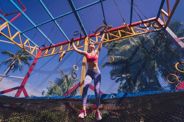 トレーニングキャンプで体操リングを使用して運動若い女性 — ストック写真