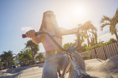 Mutlu genç kadın kaykay parkında BMX 'in tadını çıkarıyor..
