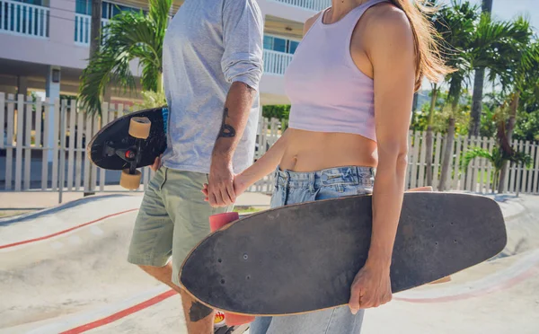 stock image Young happy couple with skateboards enjoy longboarding at the skatepark.