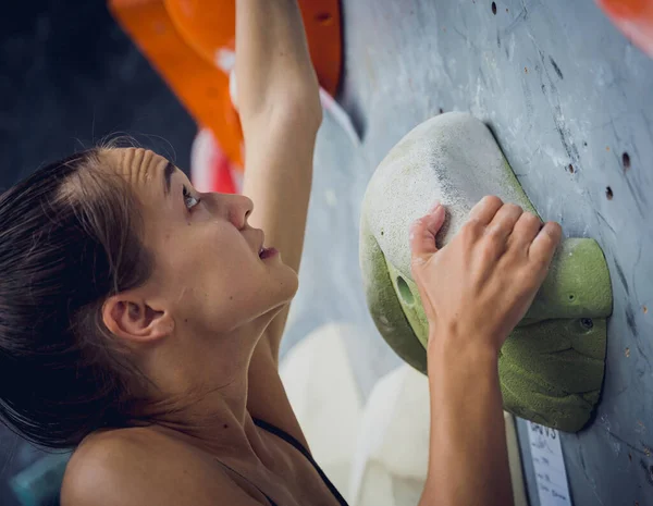 強い女性のクライマーはカラフルなグリップとロープで人工的な壁を登ります — ストック写真