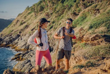 Mutlu genç çift okyanusun yakınındaki dağların zirvesine tırmanıyor..