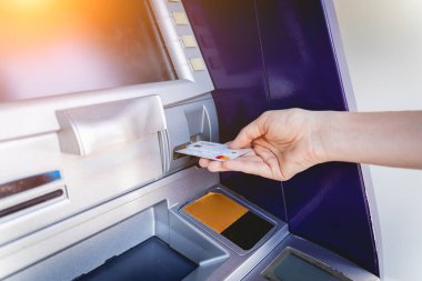 Genç bir kadın ATM 'den para çekmek için kartı kullanıyor..