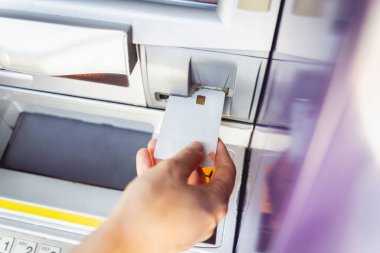 Genç bir kadın ATM 'den para çekmek için kartı kullanıyor..