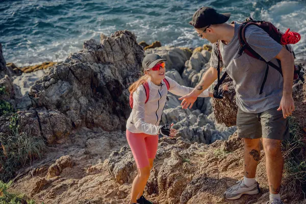 幸せな若いカップルは海の近くの山の頂上に登る — ストック写真