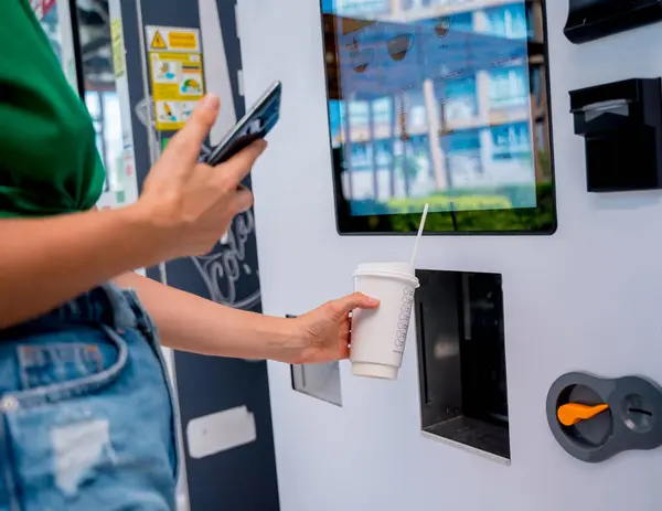 非接触支払い方法を使用して自動販売機でコーヒーを支払う若い女性 — ストック写真