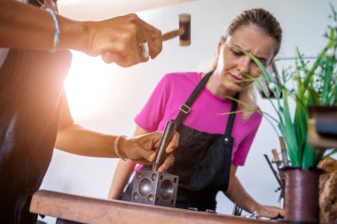 Öğretmen kuyumcu ve öğrenci atölyede mücevher yapıyor..