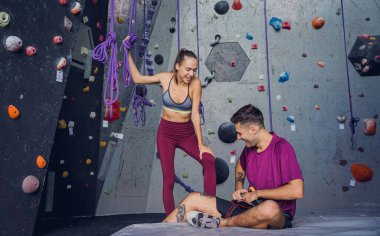 Renkli tutacakları ve ipleri olan yapay bir duvara karşı güçlü bir çift tırmanıcı.