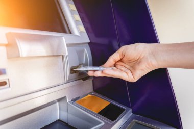 Genç bir kadın ATM 'den para çekmek için kartı kullanıyor..