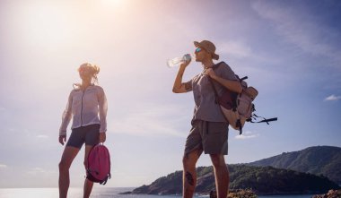 Mutlu genç çift okyanus kıyısındaki dağların tepesine tırmandıktan sonra rahatlıyor..