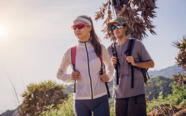 Mutlu genç çift okyanusun yakınındaki dağların zirvesine tırmanıyor..