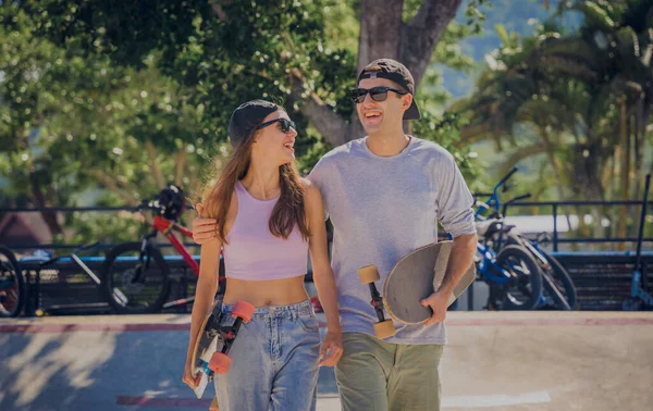 stock image Young happy couple with skateboards enjoy longboarding at the skatepark.