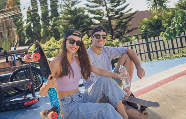 スケートボードを持つ若い幸せなカップルは スケートパークでロングボードを楽しんでいます — ストック写真