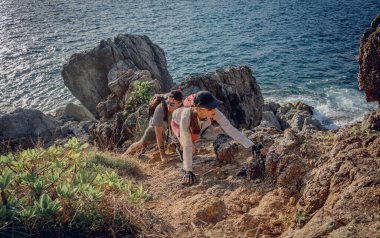 Mutlu genç çift okyanusun yakınındaki dağların zirvesine tırmanıyor..