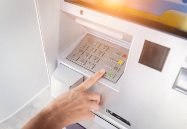 Genç bir kadın ATM 'den para çekmek için kartı kullanıyor..