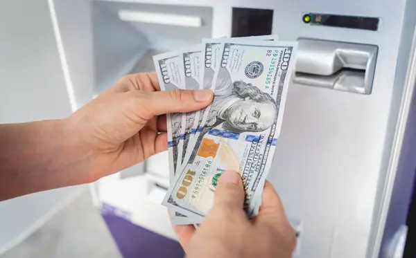 Young woman holding money in her hands after withdrawing the cash at the ATM.
