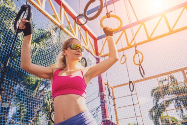 Spor kampında jimnastik yüzükleri kullanan atletik genç bir kadın..