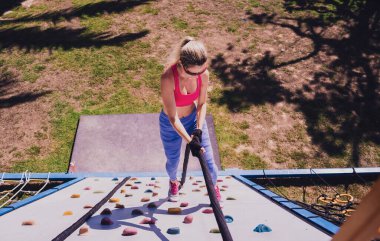 Atletik genç bayan halat kampında ip tırmanışı yapıyor.