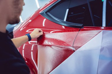 Yeni kırmızı arabaya koruyucu film yükleme işlemi