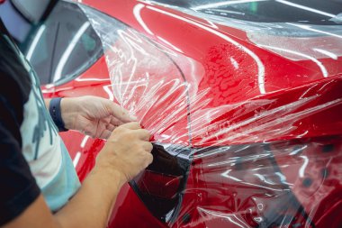 Yeni kırmızı arabaya koruyucu film yükleme işlemi