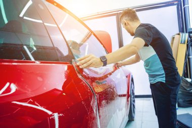 Yeni kırmızı arabaya koruyucu film yükleme işlemi