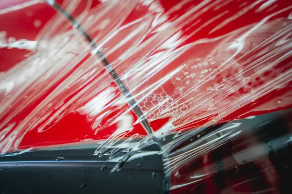 Yeni Kırmızı Arabaya Koruyucu Film Yükleme Işlemi — Stok fotoğraf