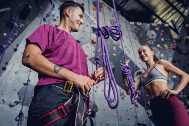 Renkli tutacakları ve ipleri olan yapay bir duvara karşı güçlü bir çift tırmanıcı.