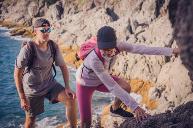 Mutlu genç çift okyanusun yakınındaki dağların zirvesine tırmanıyor..