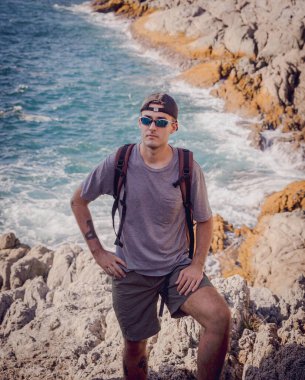 Genç adam okyanusun yakınındaki dağların tepesine tırmanır..