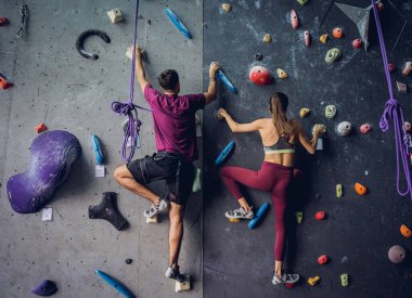 Güçlü bir çift tırmanışçı renkli tutacakları ve ipleriyle yapay bir duvara tırmanıyor.