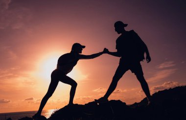 Mutlu genç çift okyanusun yakınındaki dağların zirvesine tırmanıyor..