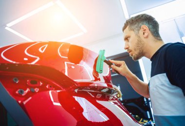 Yeni kırmızı arabaya koruyucu film yükleme işlemi