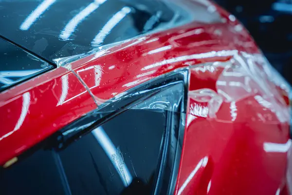 Yeni kırmızı arabaya koruyucu film yükleme işlemi