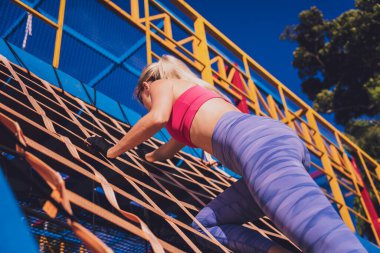 Atletik genç bayan antrenman kampında çalışıyor ve tırmanıyor.