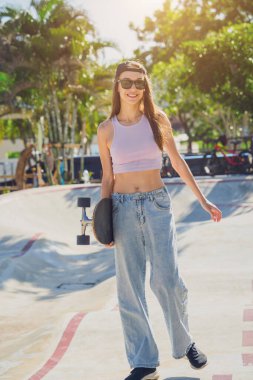 Kaykaylı mutlu genç kadın kaykayın tadını çıkarıyor..