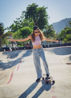 Kaykaylı mutlu genç kadın kaykayın tadını çıkarıyor..