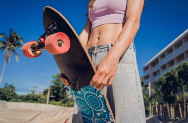 Kaykaylı mutlu genç kadın kaykayın tadını çıkarıyor..