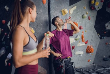 Renkli tutacakları ve ipleri olan yapay bir duvara karşı güçlü bir çift tırmanıcı.