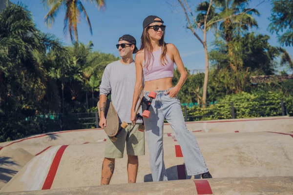 stock image Young happy couple with skateboards enjoy longboarding at the skatepark.