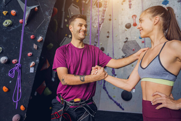 A strong couple of climbers against an artificial wall with colorful grips and ropes