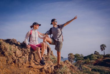Mutlu genç çift okyanusun yakınındaki dağların zirvesine tırmanıyor..