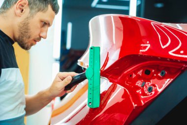 Yeni kırmızı arabaya koruyucu film yükleme işlemi