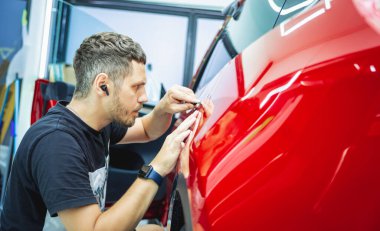 Yeni kırmızı arabaya koruyucu film yükleme işlemi