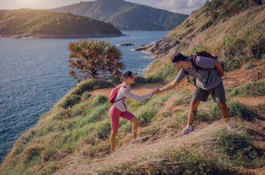 Mutlu genç çift okyanusun yakınındaki dağların zirvesine tırmanıyor..