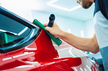 Yeni kırmızı arabaya koruyucu film yükleme işlemi